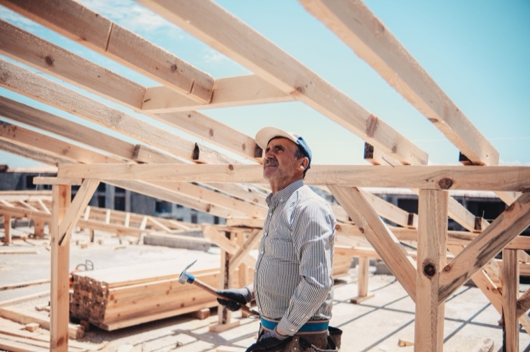 A carpenter checking a wooden roof frame on a building site